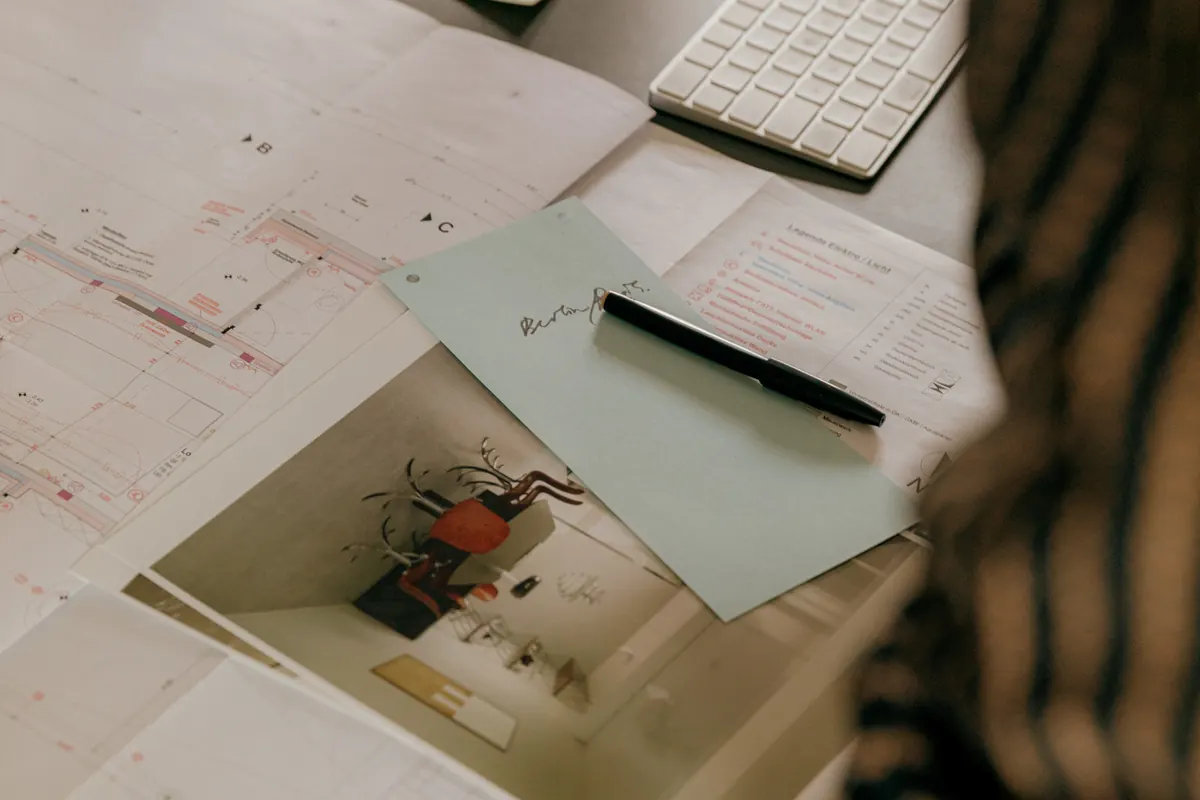 Construction drawings and a finish sample marked up on a studio desk